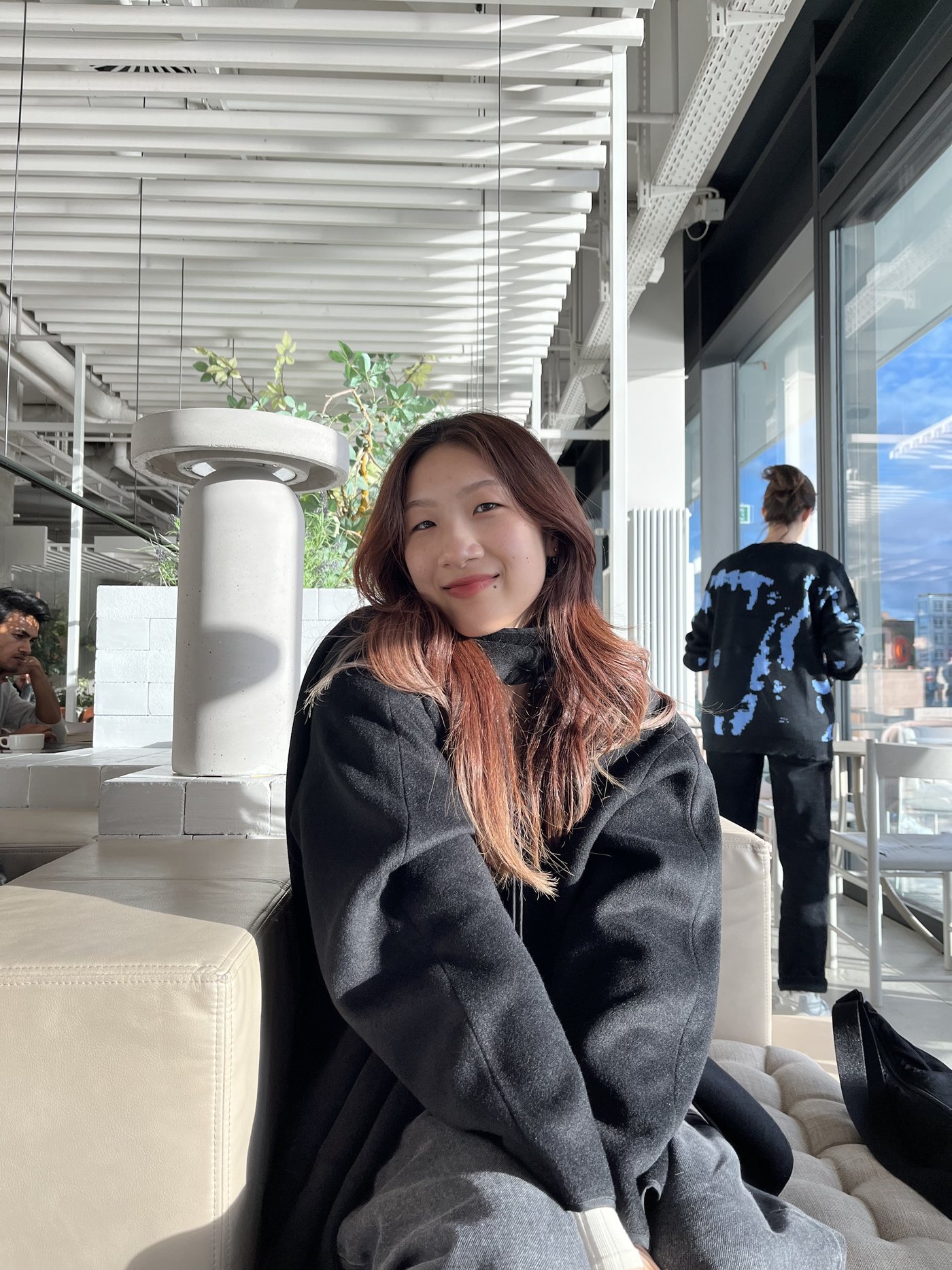 Serina Li smiling in a bright, sunlit cafe